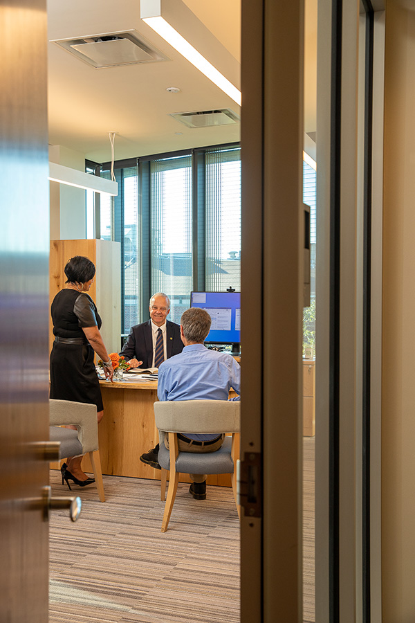 Dean Paulo Goes talks with staff in his office.